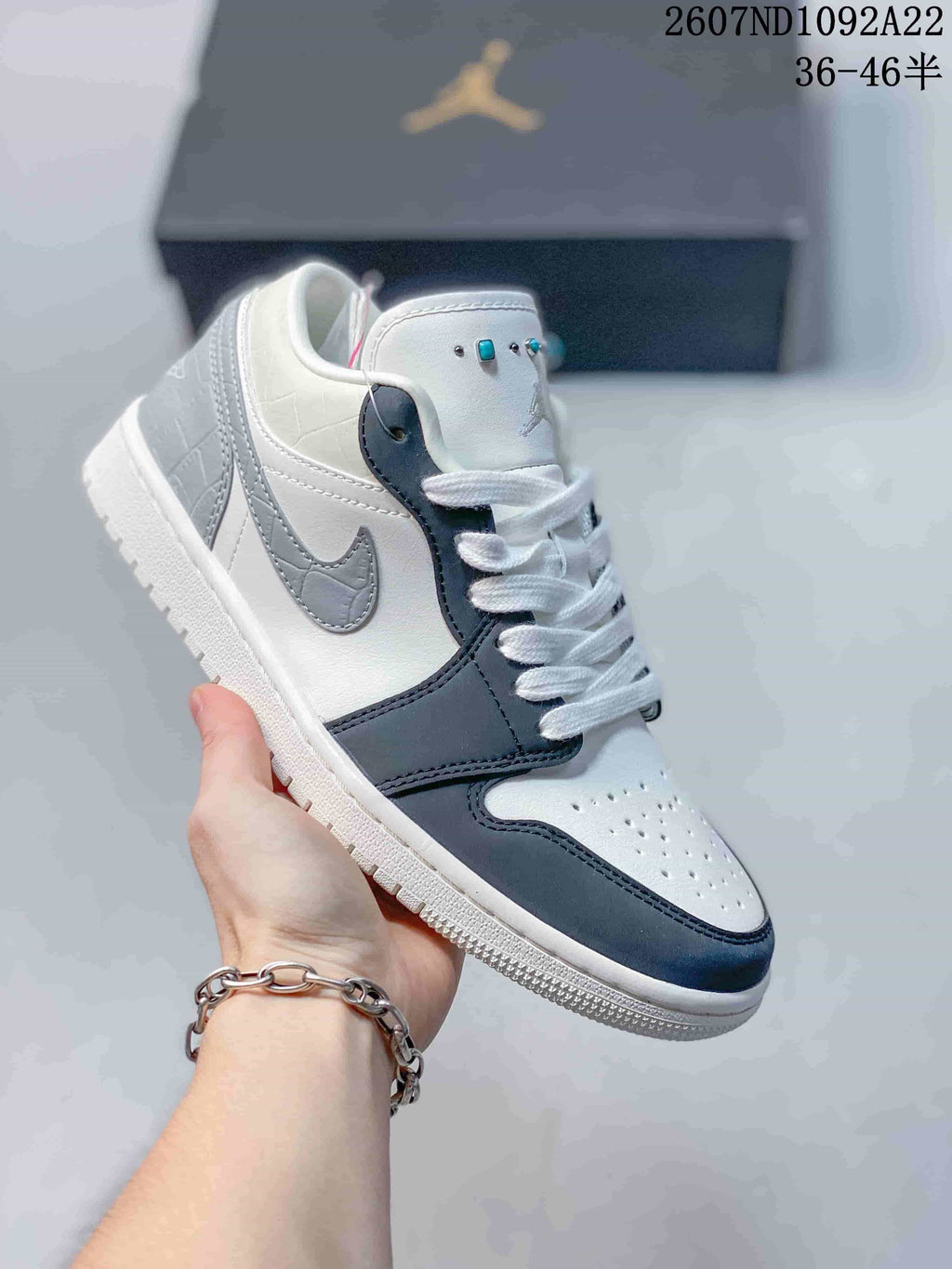 White and dark blue low-top Jordan sneaker with a gray Swoosh and turquoise lace accents.