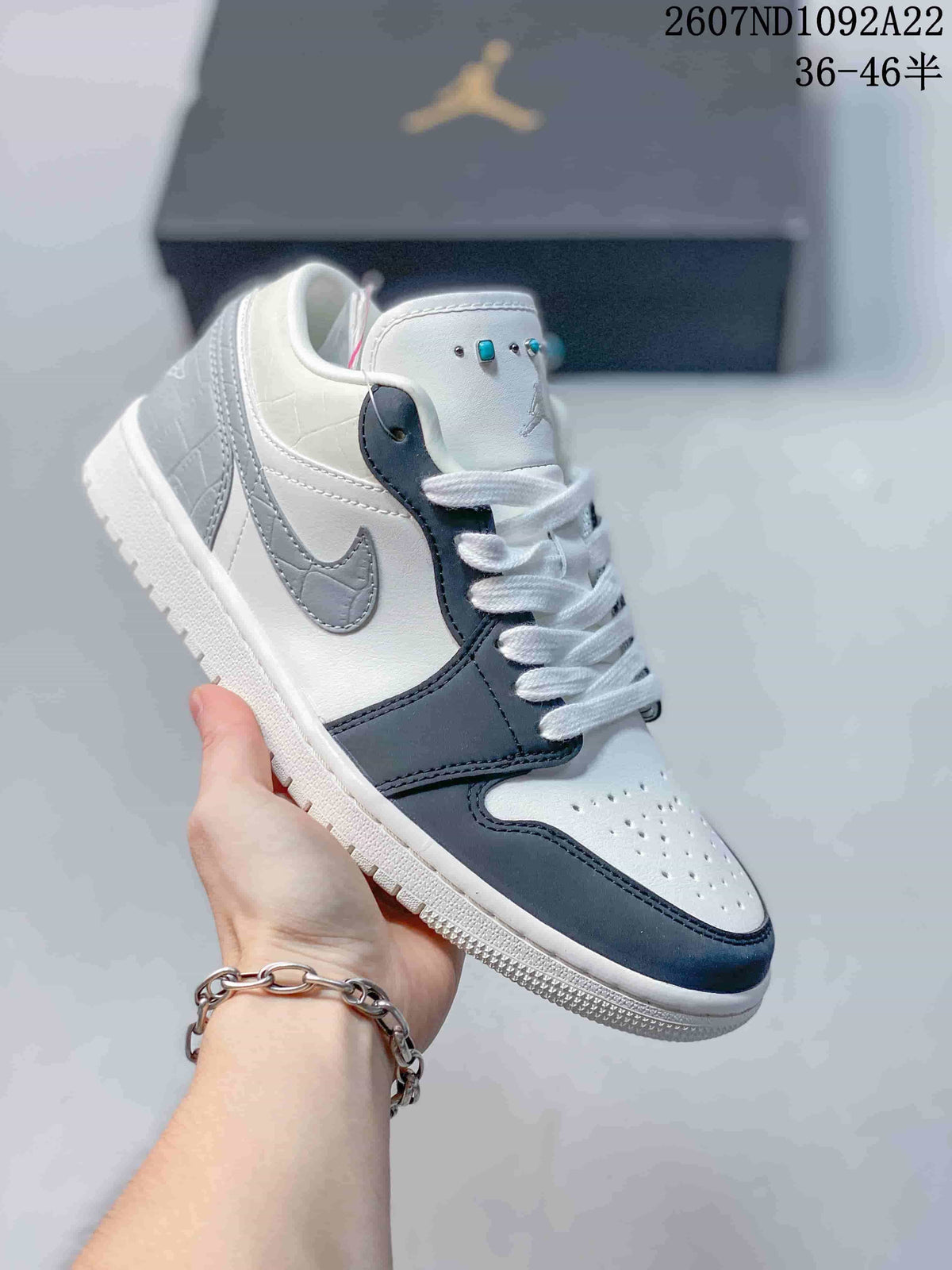White and dark blue low-top Jordan sneaker with a gray Swoosh and turquoise lace accents.