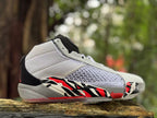 Side view of a white Jordan XXXVIII shoe with black and red geometric accents.