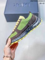 Side profile of the green and brown sneaker showing layered panels, contrast stitching, speckled sole, and yellow traction lugs.