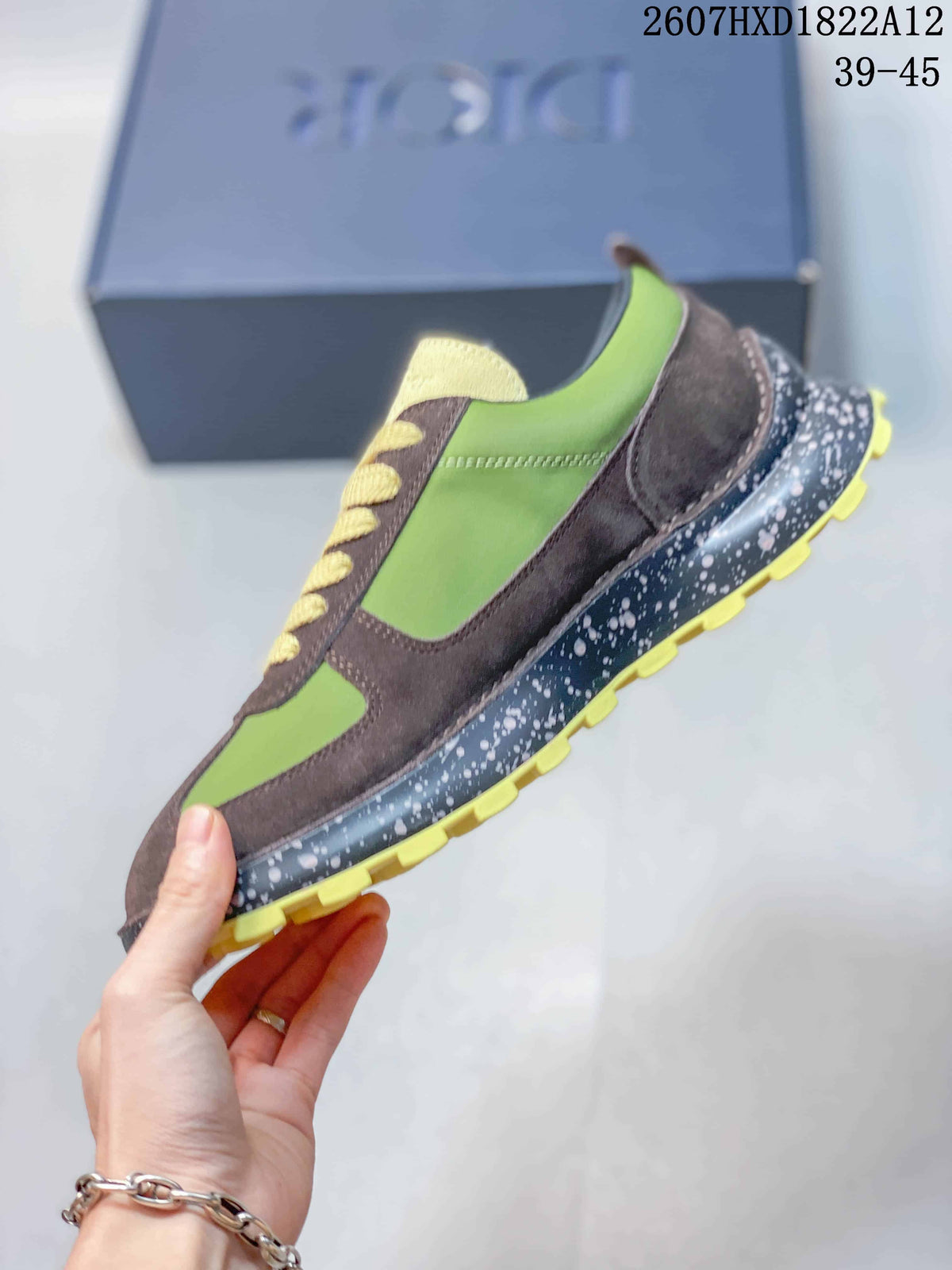 Side profile of the green and brown sneaker showing layered panels, contrast stitching, speckled sole, and yellow traction lugs.