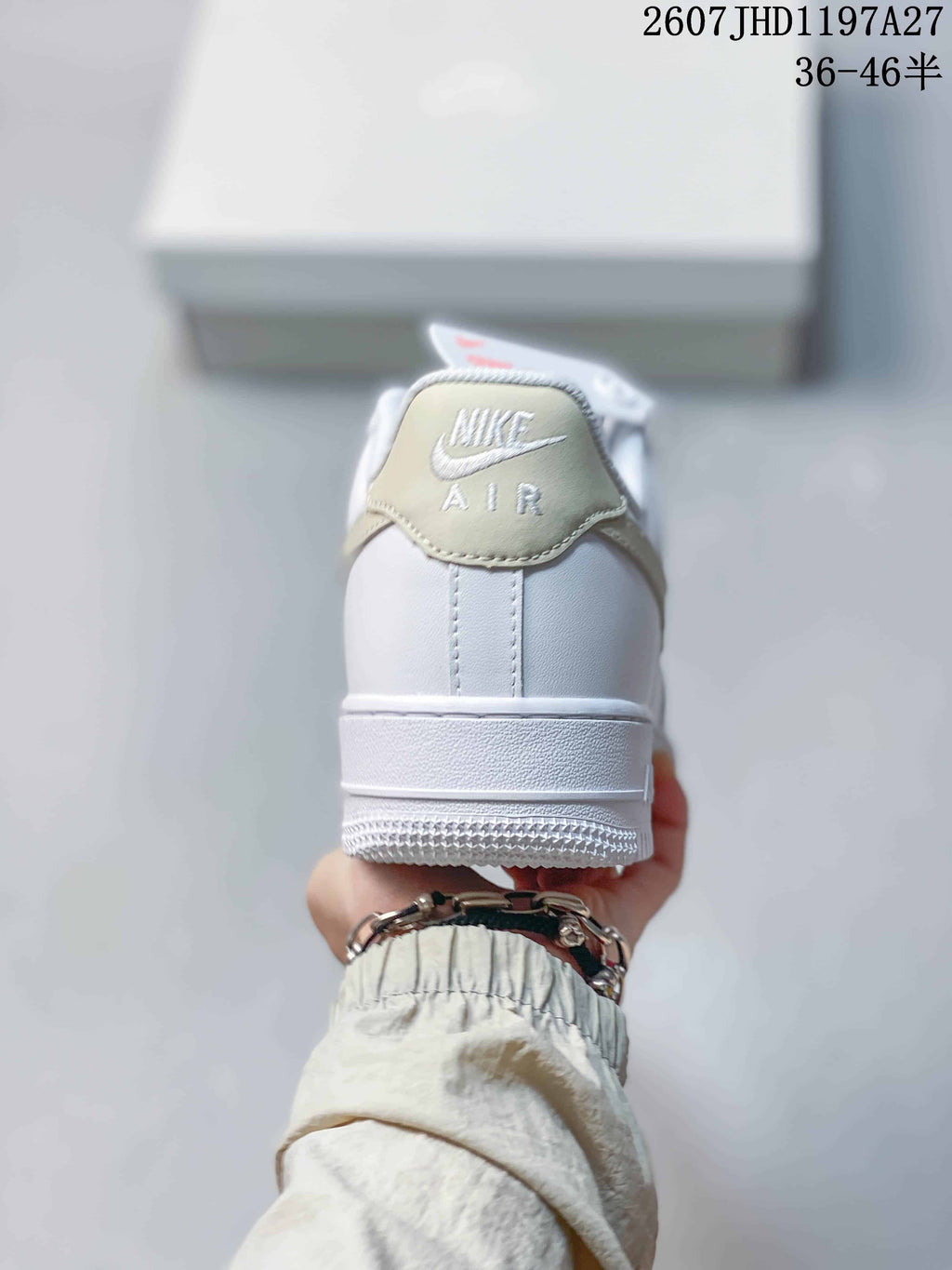 Rear view of the white sneaker showing the padded collar, heel stitching, pale beige accent, and Air branding.