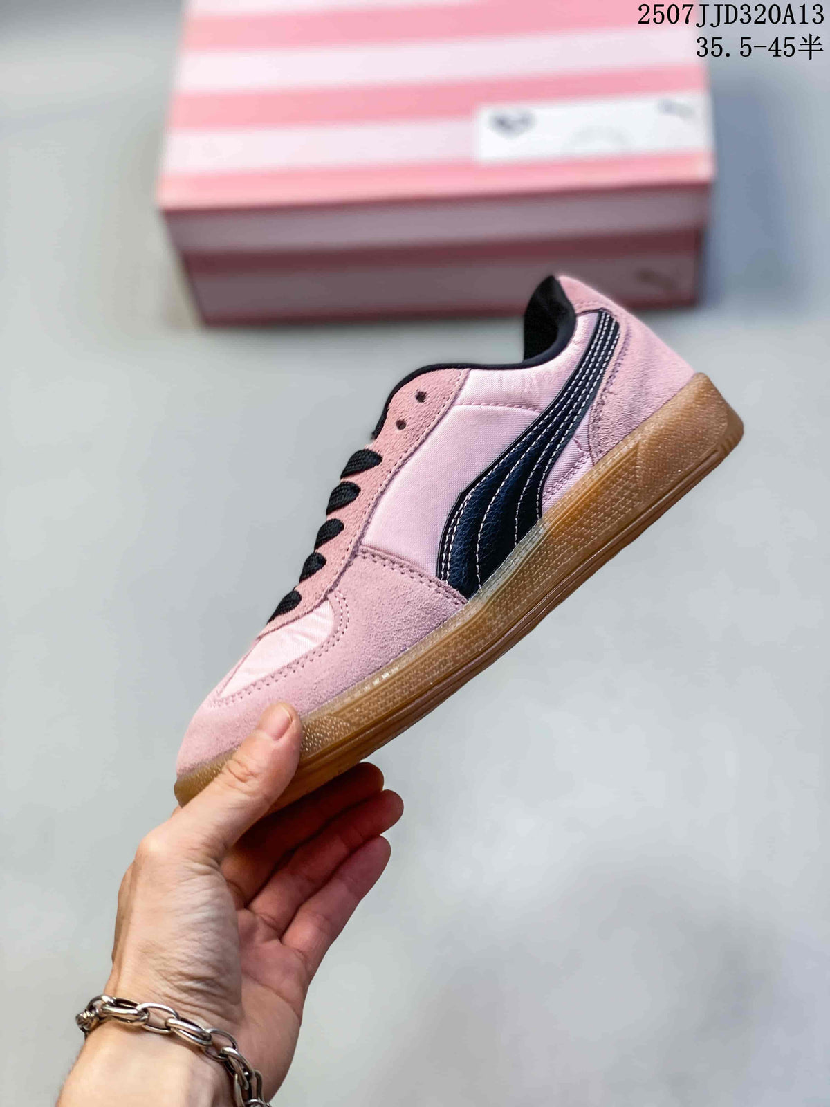 Side profile of the pink low-top sneaker with black side branding, black laces and a gum outsole.