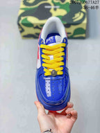 Top view of a blue low-top sneaker with perforated toe detailing, yellow laces, and BAPE STA tongue branding.