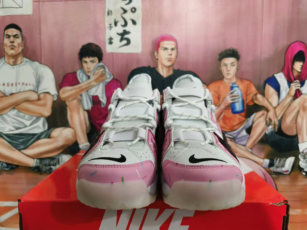 Front view of white and pink Nike sneakers with black Swoosh details and sprinkle-like accents.