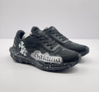 Angled front view of the black sneaker pair with contrasting white side artwork.