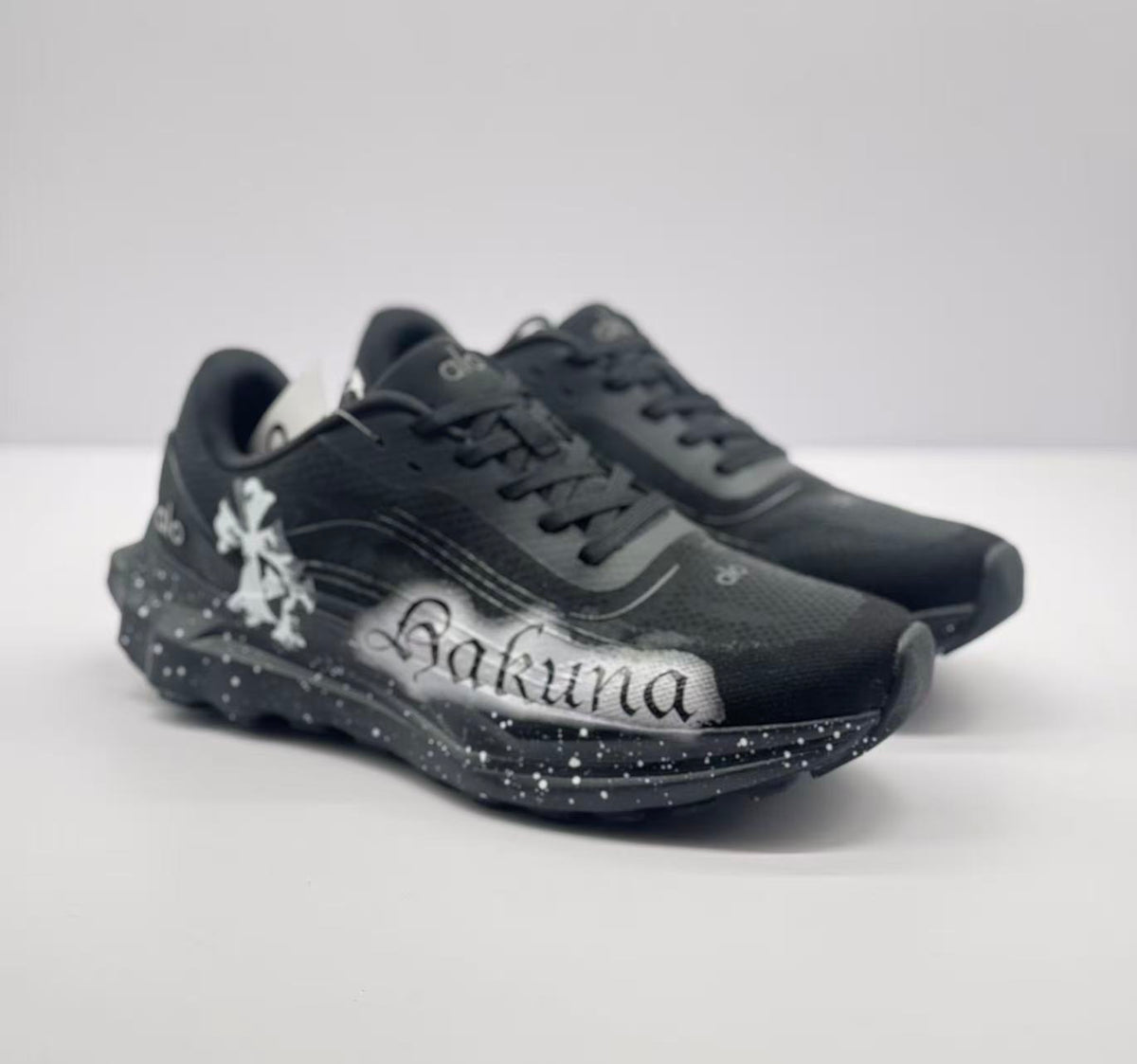 Angled front view of the black sneaker pair with contrasting white side artwork.