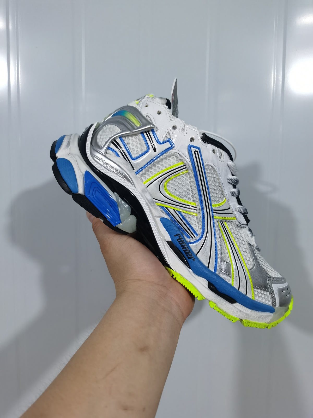 Angled close-up of a white and blue Puma Runner sneaker with silver overlays, neon yellow accents, and mesh panels.