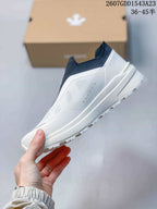 Side profile showing the white textured upper, navy collar, and thick midsole