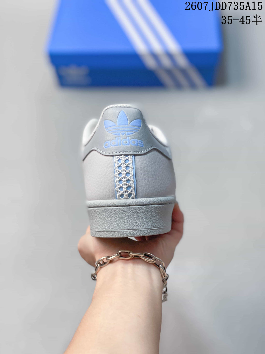 Rear view of the sneaker showing the blue trefoil logo and textured heel detail.