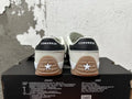Rear view of cream Converse sneakers with black heel tabs and gum-colored soles