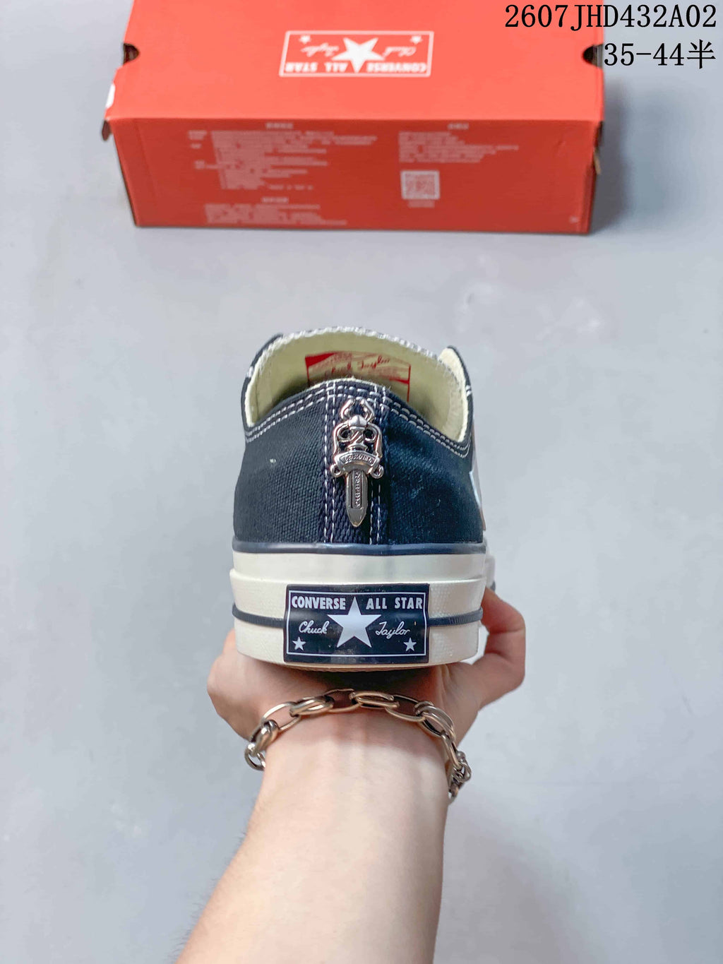 Rear view of the navy sneaker showing its heel label and a decorative metal detail.