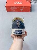 Rear view of the navy sneaker showing its heel label and a decorative metal detail.