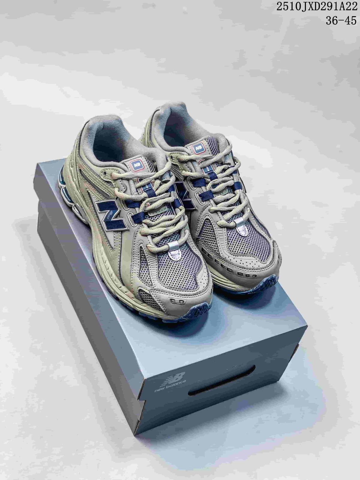 Pair of grey and silver New Balance M1906AD sneakers with navy accents on a shoebox