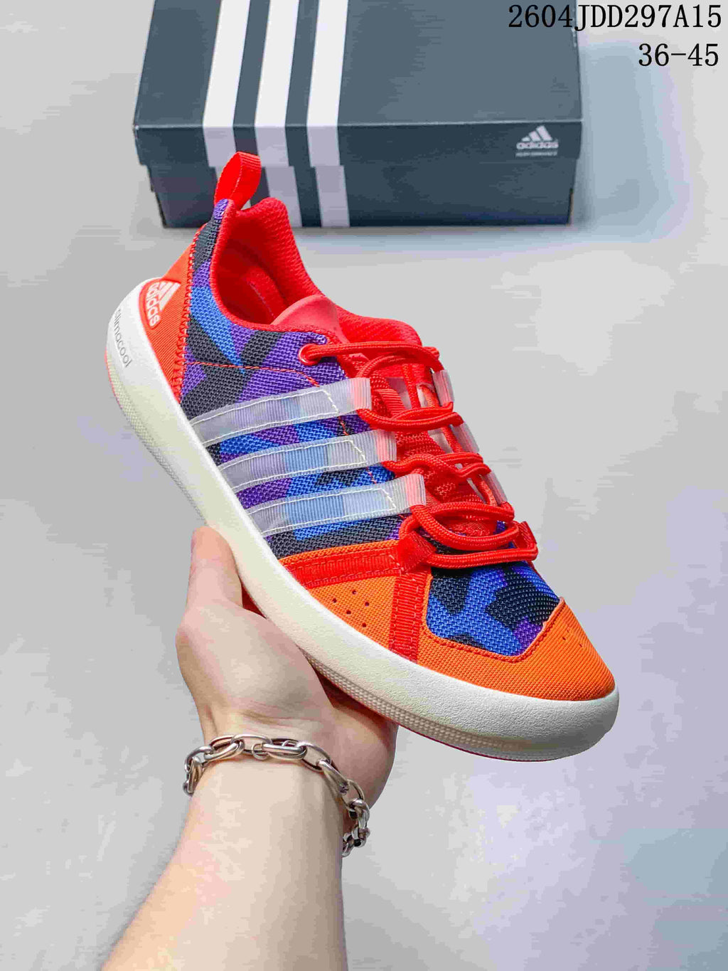 Angled side view of the orange, blue and purple Adidas shoe with red laces and a white midsole.