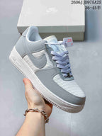 Angled side view of the light grey and white Nike Air Force 1 '07 sneaker showing the Swoosh, padded collar, white midsole, and textured outsole.