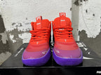 Front view of red Puma Melo basketball shoes with purple toes and soles.