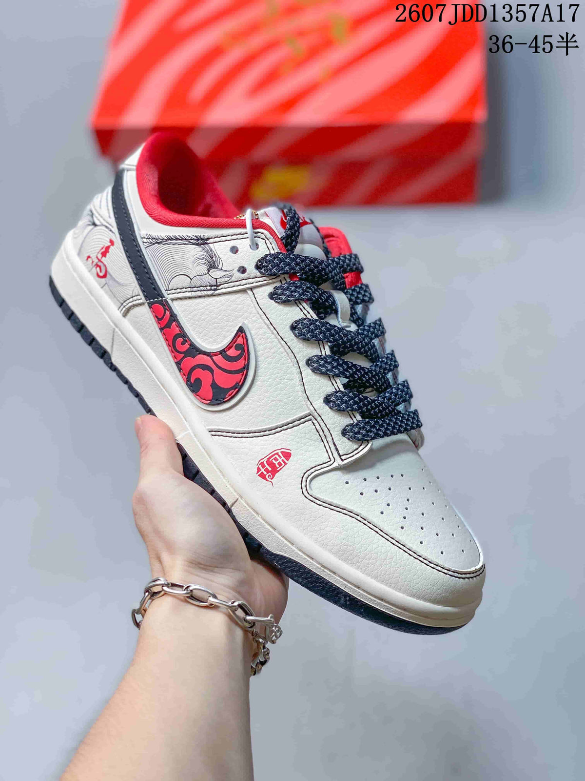 Cream low-top sneaker with black and red patterned side detailing, dark laces and a dark outsole.