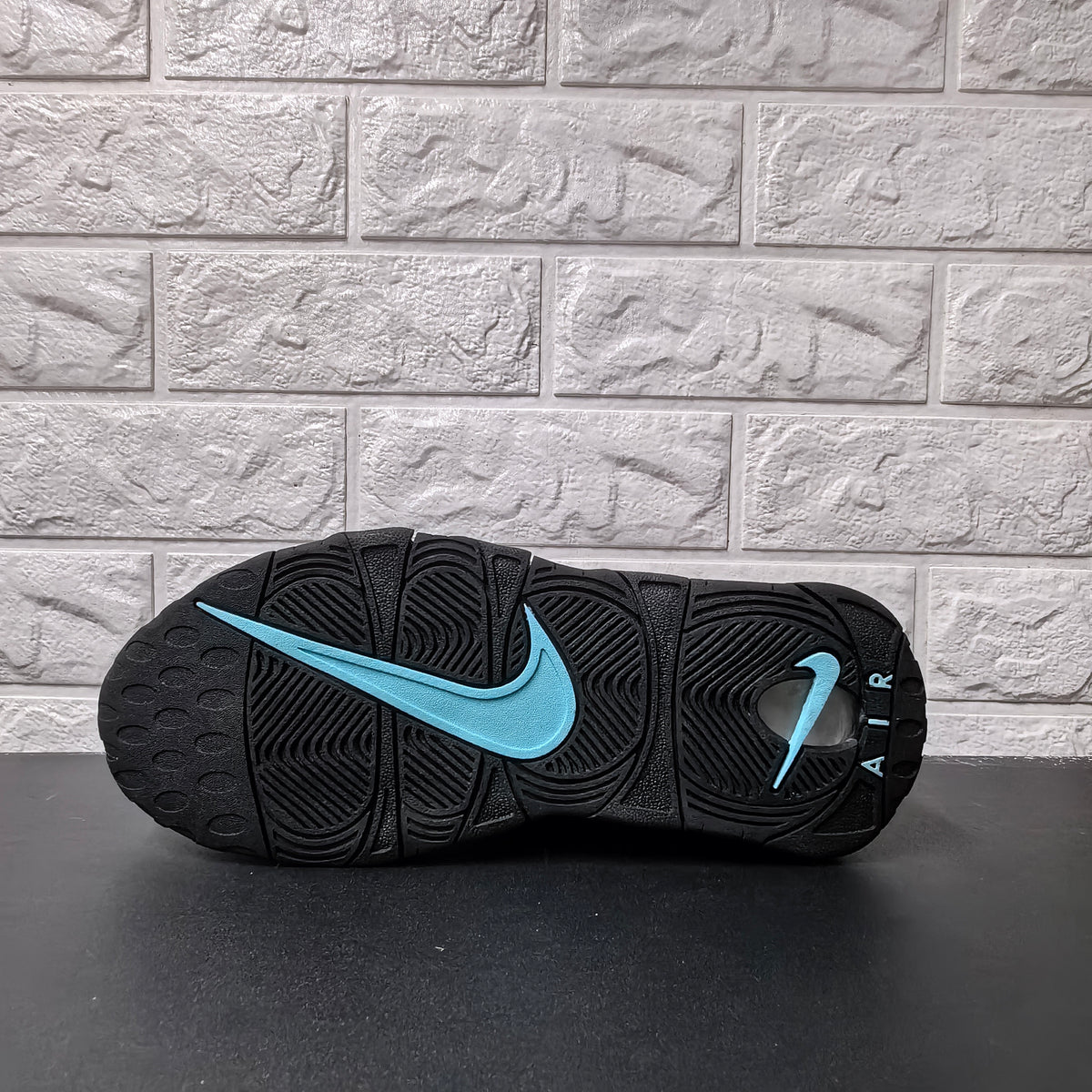 Outsole view with black tread and a light blue Nike Swoosh