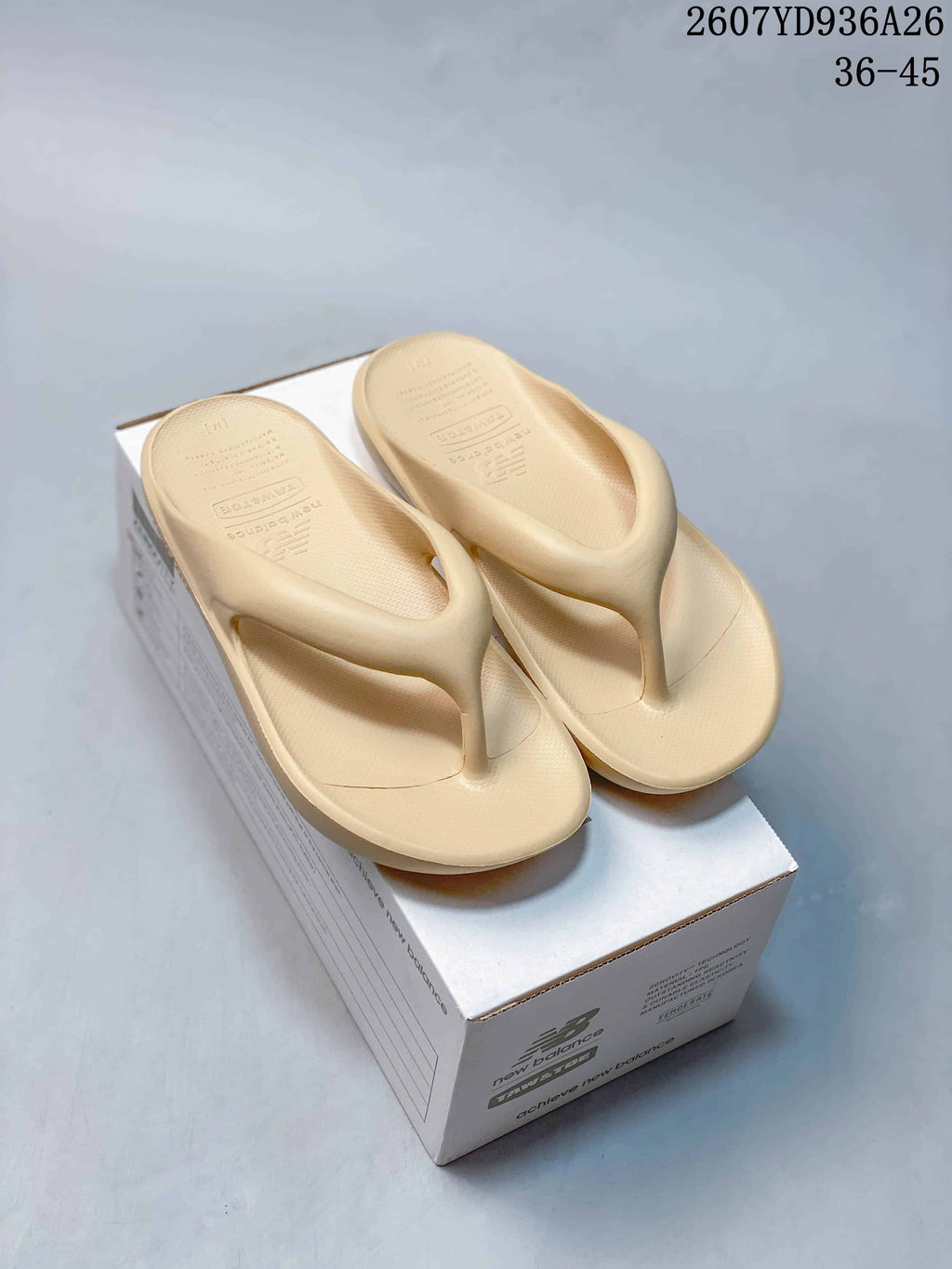 Pair of beige New Balance thong sandals displayed on a branded shoe box; image text shows style code 2607YD936A26 and sizes 36–45.