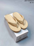 Pair of beige New Balance thong sandals displayed on a branded shoe box; image text shows style code 2607YD936A26 and sizes 36–45.