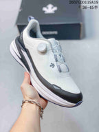 Angled side view of the white DESCENTE running shoe showing the BOA-style dial, dark toe overlay, and layered sole.
