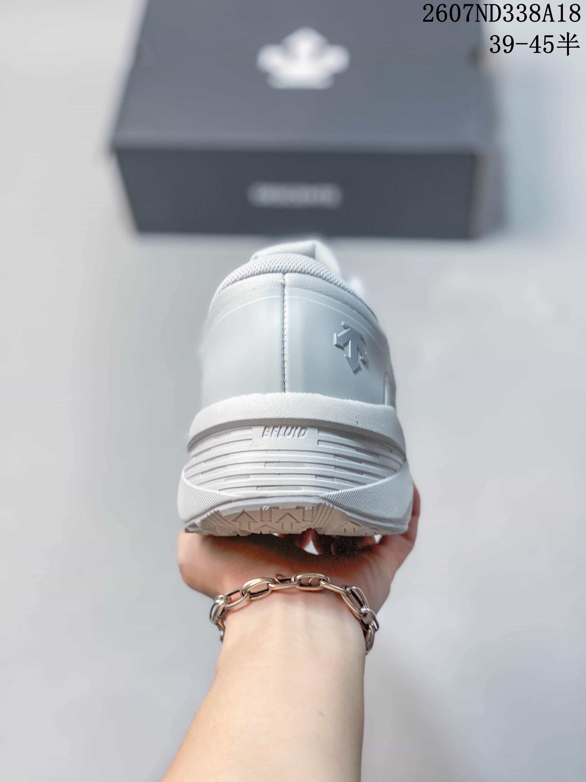 Rear view of the white sneaker showing the padded heel collar, heel branding, and textured outsole edge.