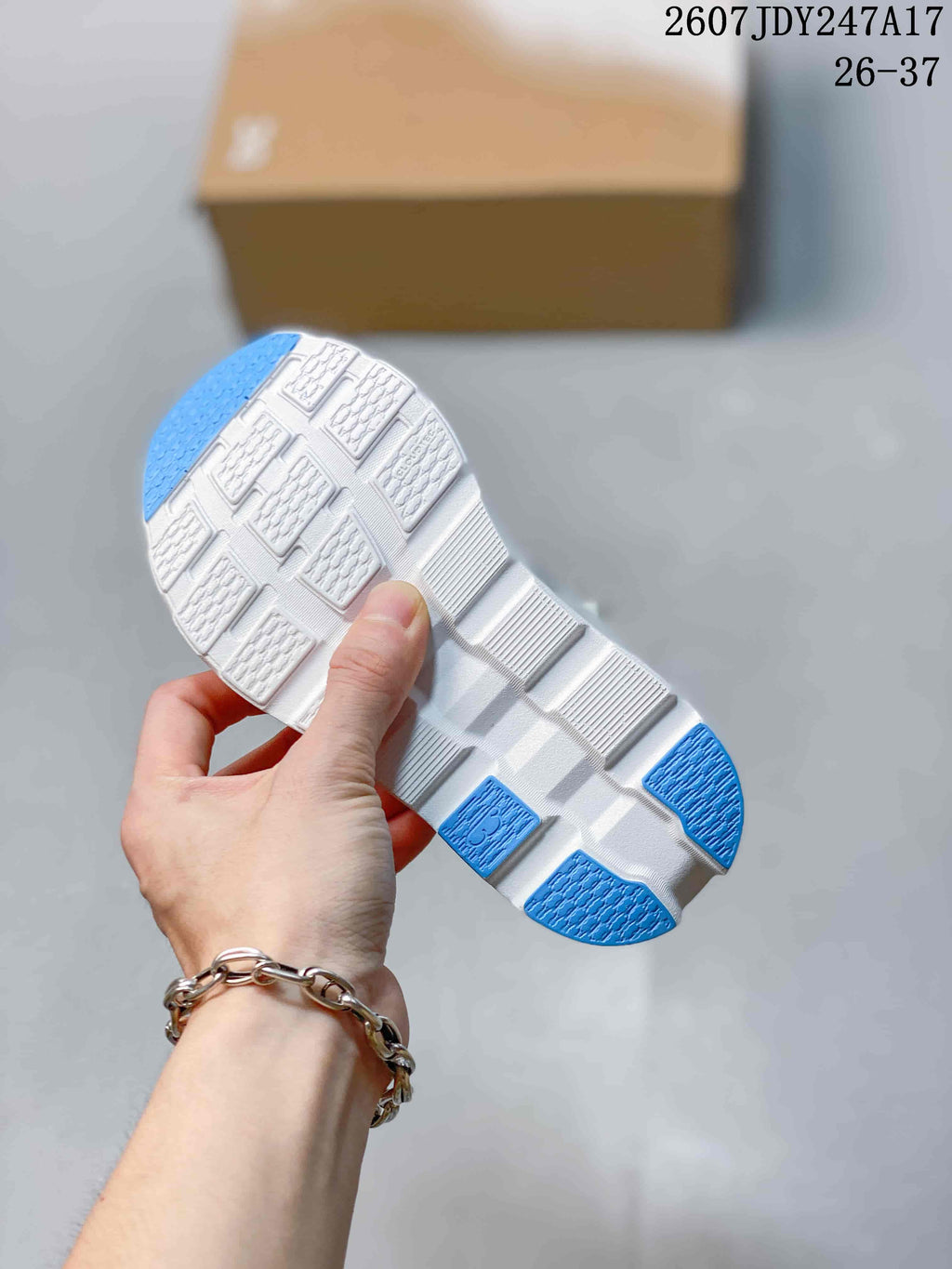 Close view of the white outsole with segmented tread blocks and blue traction sections.