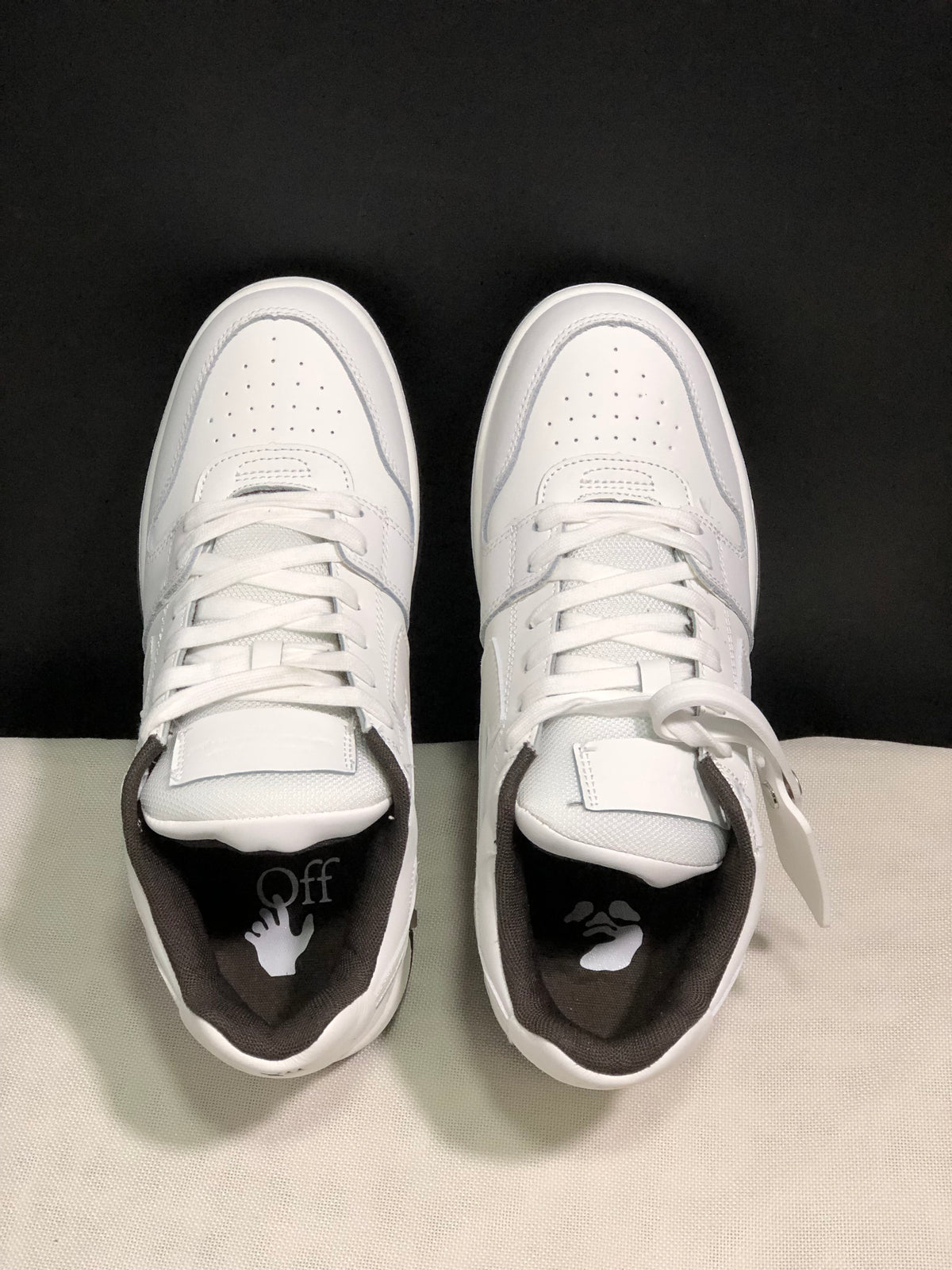Top view of the white sneaker pair showing perforated toe boxes, laces, tongues, and dark insoles.