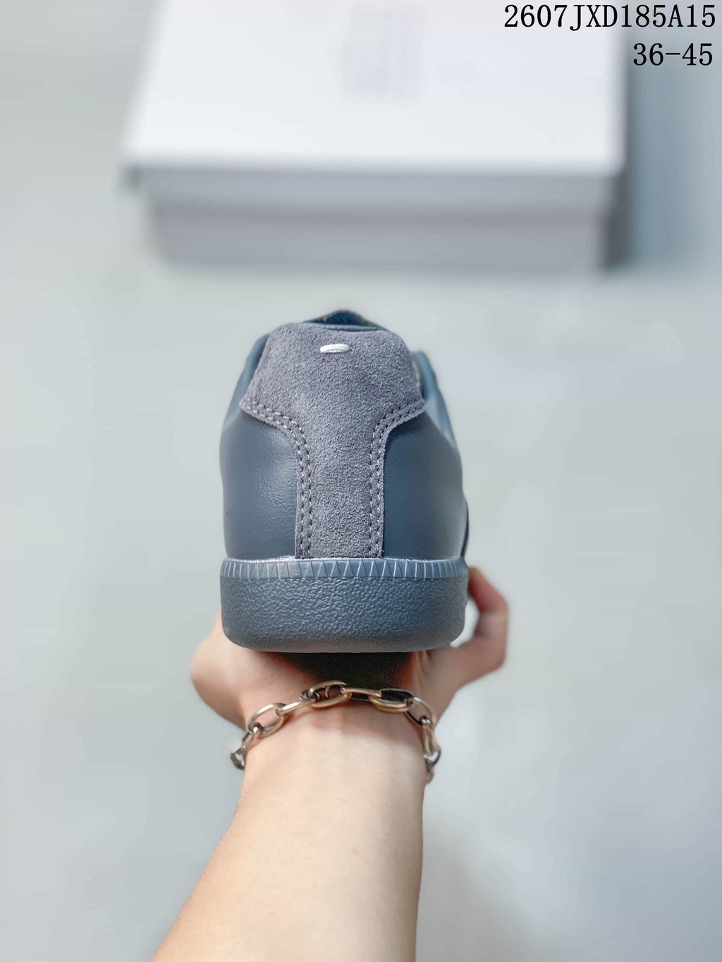 Rear view of the gray sneaker showing the textured heel panel, tonal stitching, and low rubber heel section.