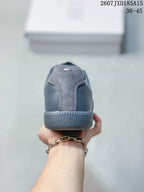 Rear view of the gray sneaker showing the textured heel panel, tonal stitching, and low rubber heel section.