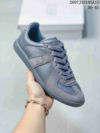 Close side view of a gray paneled sneaker with tonal laces and a matching textured outsole.