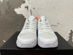 Front view of silver and white basketball shoes showing laces, perforated toe panels, and Kobe tongue emblems.