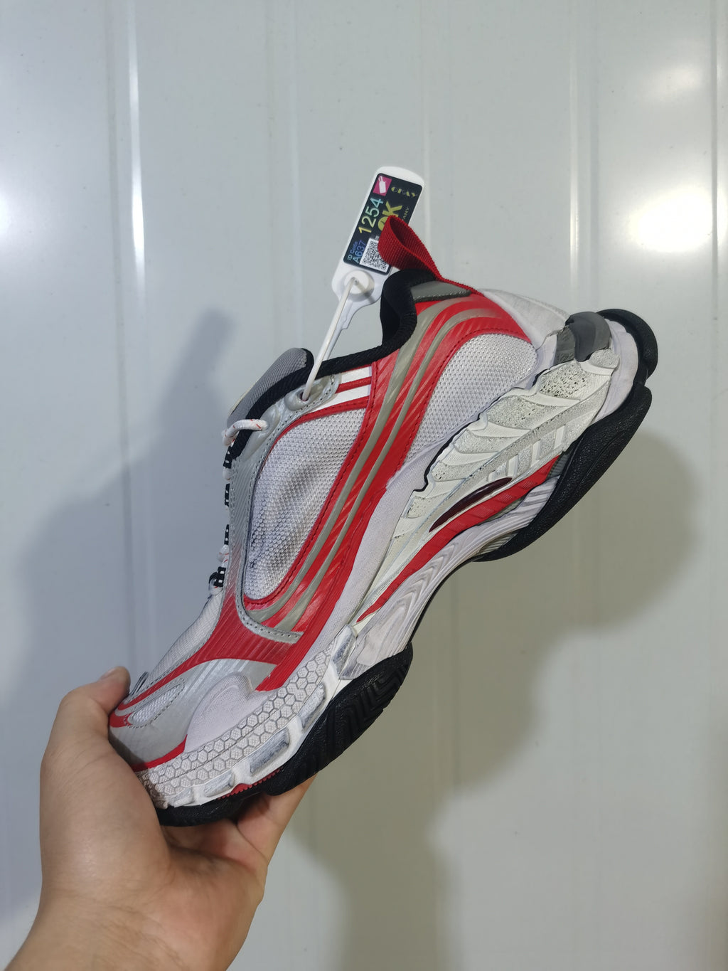 Top and side view of the ASICS 1169 sneaker showing mesh panels, layered overlays and black outsole.
