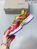 Side profile showing the red mesh upper, neon green ASICS branding and layered white midsole.