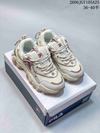 Pair of cream FILA Fusion chunky sneakers with mauve and green accents on a shoe box