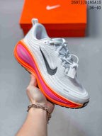 Angled side view showing the white upper, black side branding, and orange and pink midsole accents.