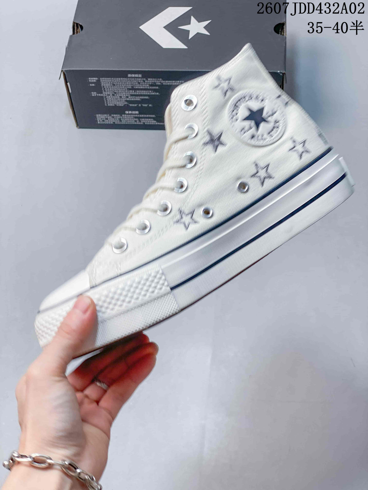 Side view of the cream high-top sneaker with embroidered stars, metal eyelets, and platform-style sole.