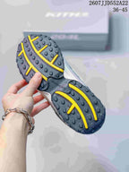 Close view of the dark outsole with yellow traction lines and raised circular lugs.