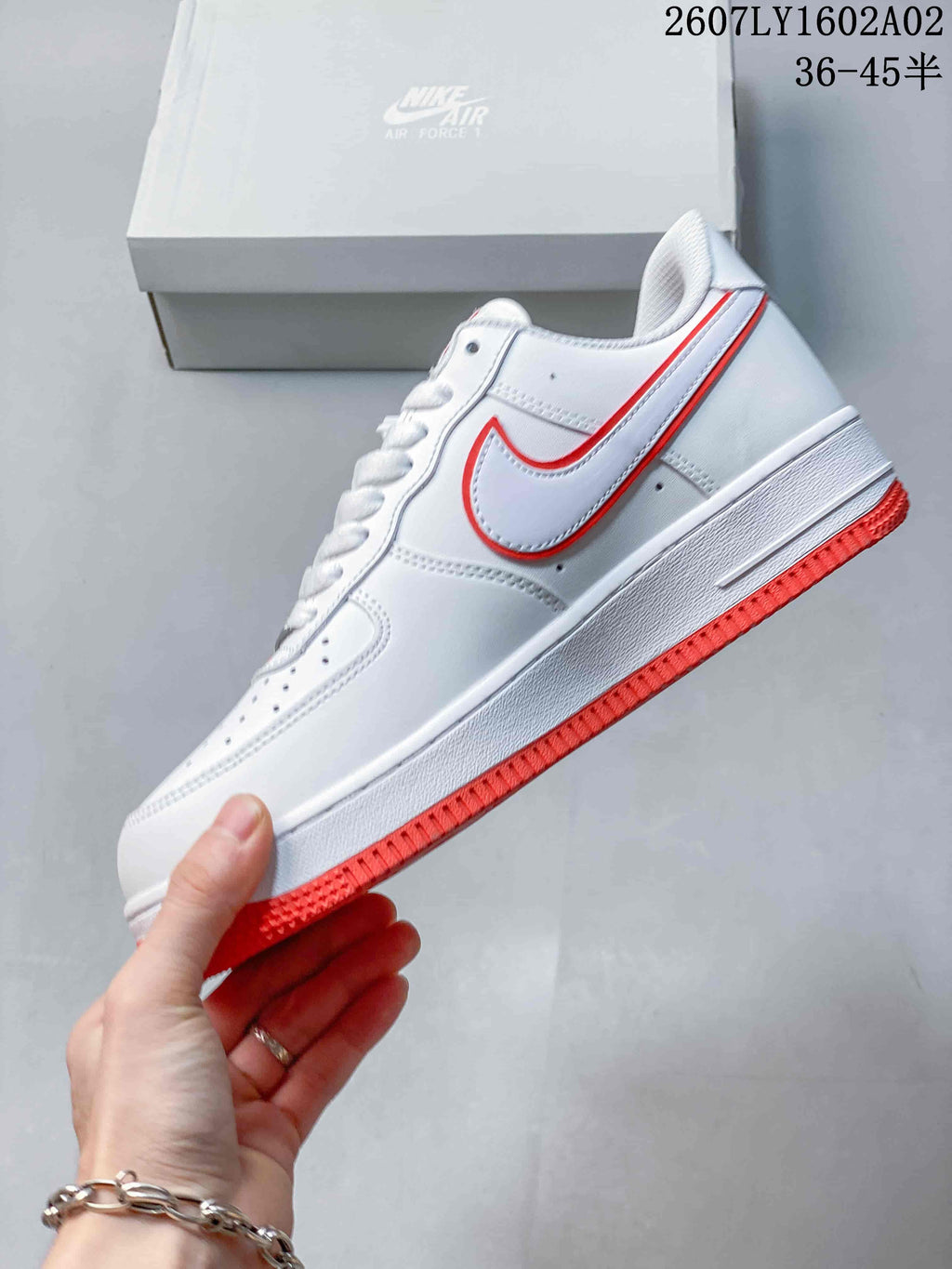 Side view of a white Nike Air Force 1 ’07 sneaker with a red-trimmed Swoosh and red outsole.