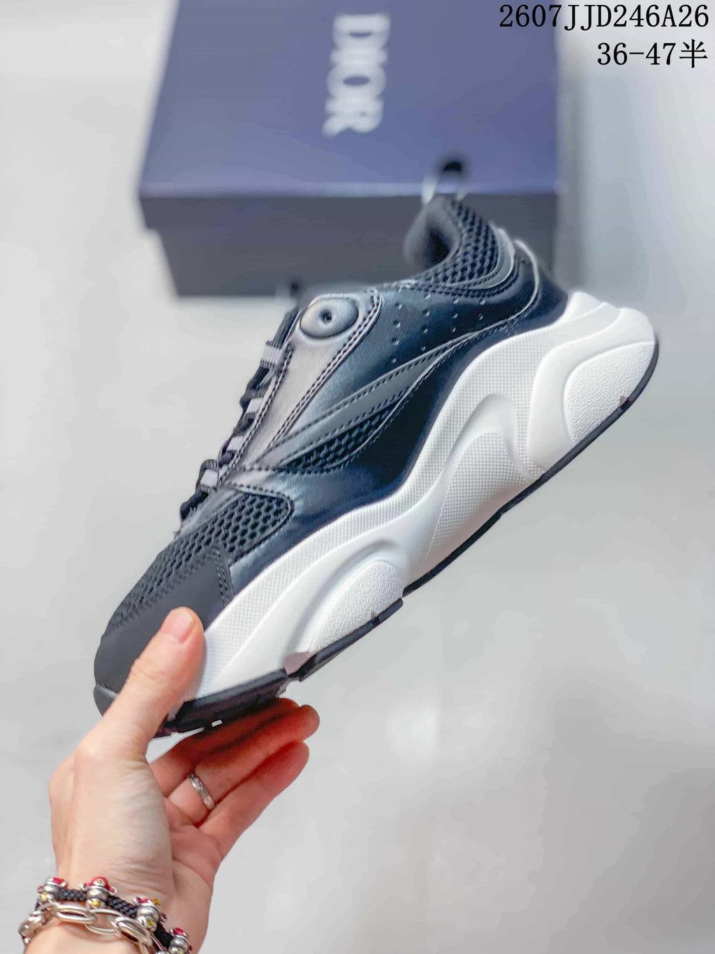 Side profile of a black and white Dior low-top sneaker showing the mesh-style upper, lace-up construction, and thick midsole.