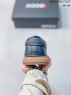 Rear view of a dark navy sneaker showing the stitched heel panel and contrasting gum-colored sole.
