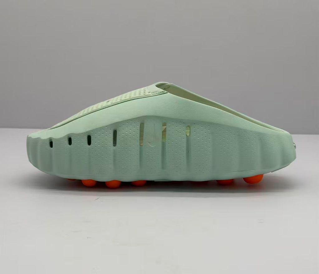 Opposite side profile showing ventilation openings, the sculpted light green sole, and orange circular outsole elements.