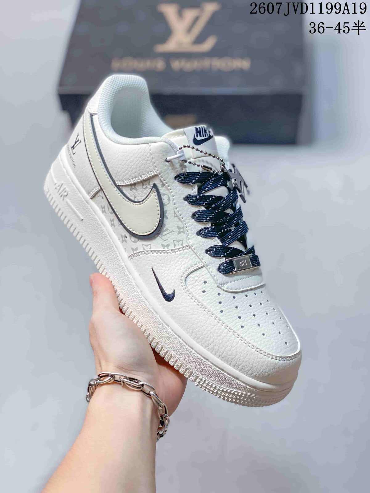 White Nike low-top sneaker held by hand, showing patterned side panels, dark Swoosh trim, Air midsole branding, and dark laces.
