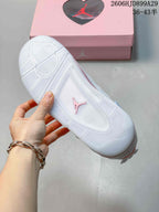 Outsole view of a white Air Jordan 4 Retro sneaker with a pink Jumpman emblem