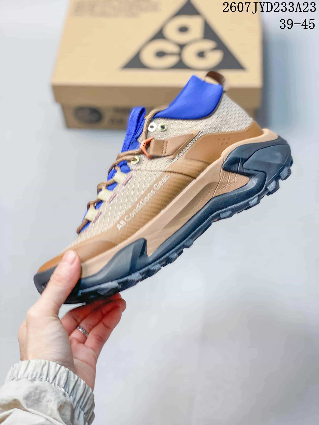 Side profile showing the tan and textured upper, blue collar, layered overlays, and rugged black sole.