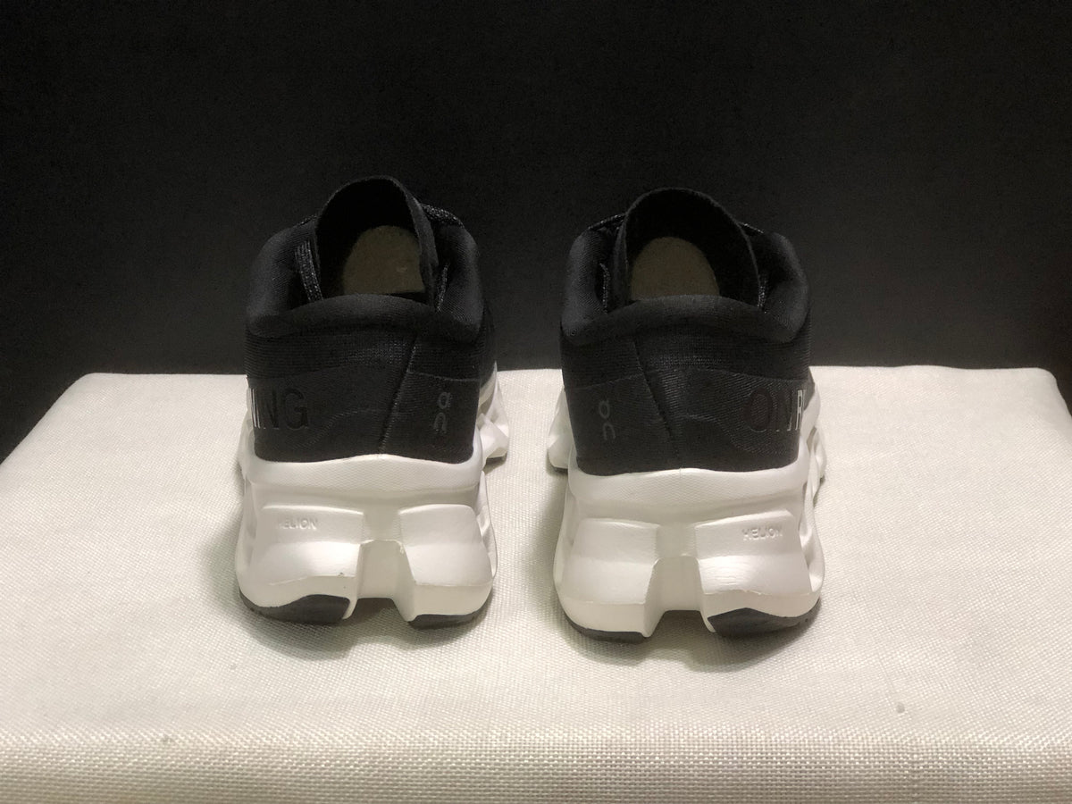 Rear view of the black sneakers showing padded collars, heel branding, and white midsoles.