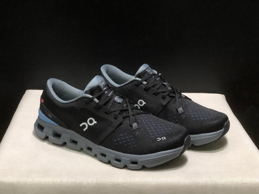 Three-quarter view of the black lace-up shoes with gray soles and blue heel accents.