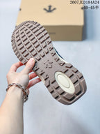 Close view of the sneaker outsole showing a block-pattern tread and central DESCENTE-style emblem.