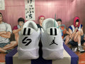 Rear view of white Jordan sneakers with black heel logos and striped heel tabs